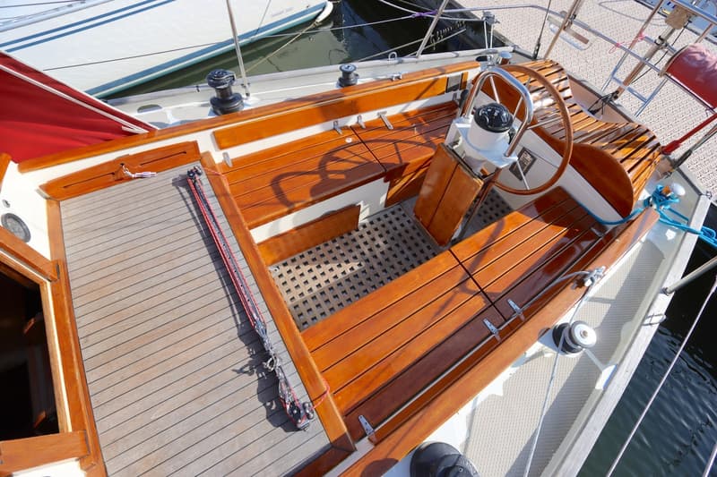 De foto toont de cockpit van een zeilboot met houten banken, een stuurwiel en een kompas. — Koopmans 36