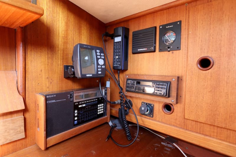 Een houten paneel met diverse elektronische apparatuur, waaronder een Garmin GPS, een Sony radio en een Shipmate marifoon.