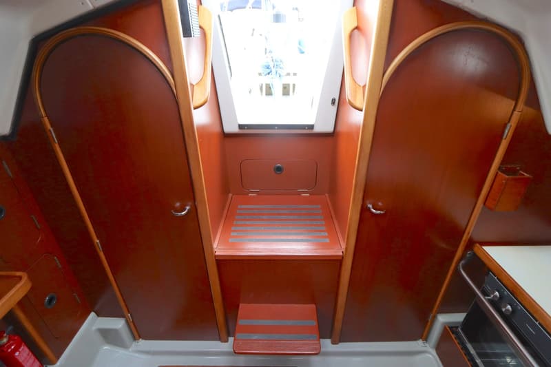 De foto toont de kajuitingang van een boot met houten deuren, een luik en een trapje. — Dehler 34 Optima 106