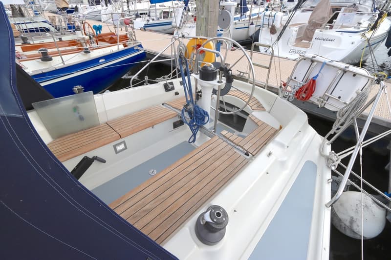 De kuip van een zeilboot met een stuurwiel, kompas, houten banken en een blauw touw. — Dehler 34 Optima 106