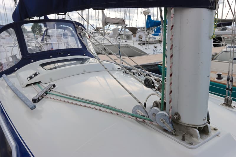 Een close-up van het dek van een zeilboot met touwen, blokken, een mast en een buiskap. — Dehler 34 Optima 106