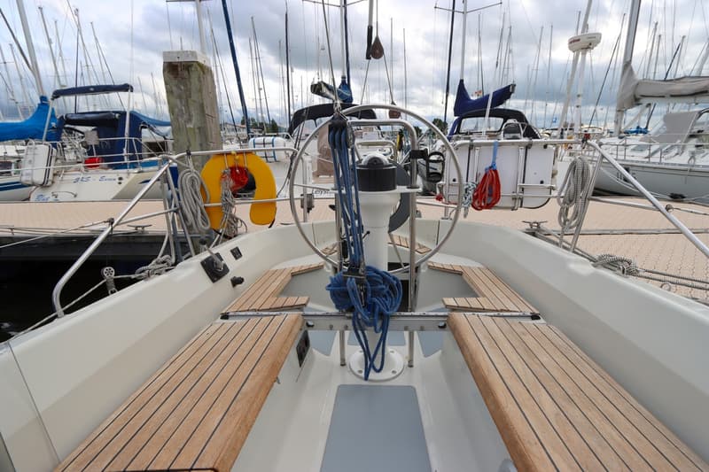 De foto toont de kuip van een zeilboot met een stuurwiel, omringd door houten banken en touwen. — Dehler 34 Optima 106
