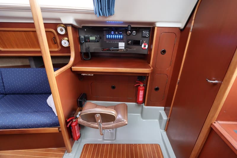 De foto toont een interieur van een boot met een navigatiehoek, zitbank, en brandblussers. — Dehler 34 Optima 106