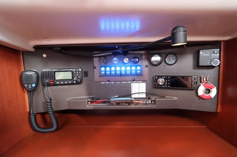 Een close-up van een bedieningspaneel met diverse elektronica, schakelaars en meters in een bootinterieur.