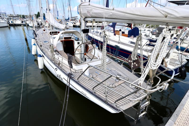 Een witte zeilboot met de naam "Salsa" ligt aangemeerd in een haven, omringd door andere boten. — RJ 140