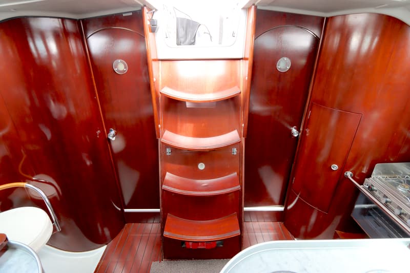 De foto toont een interieur van een boot met een houten trap, twee houten deuren en een fornuis. — Beneteau First 41S5