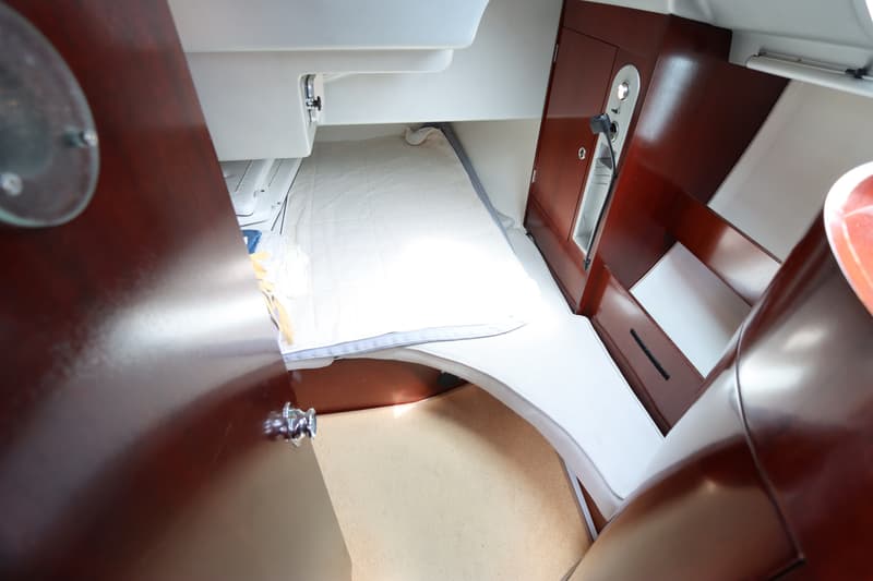 De foto toont een kajuit met een bed, een bankje, een kast en een tapijt op de vloer. — Beneteau First 41S5