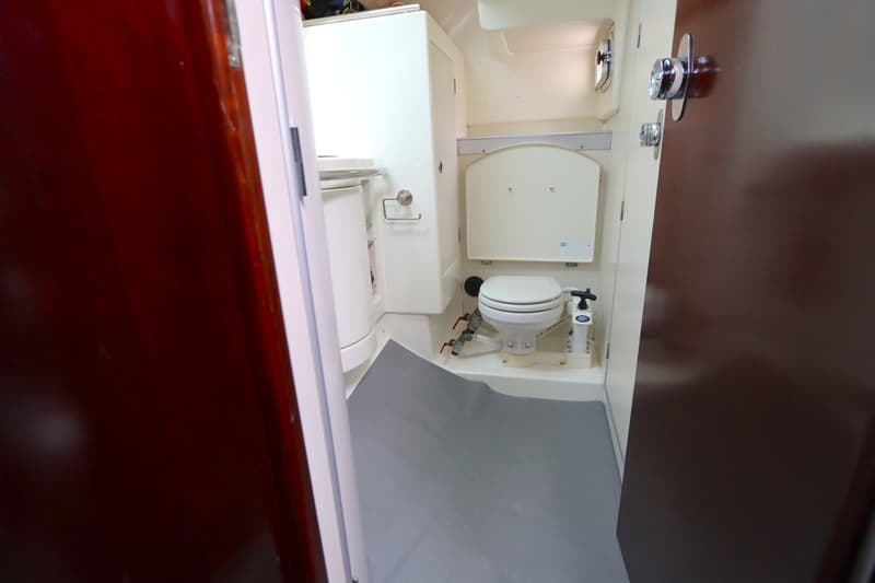 Een witte toiletruimte met een toilet, een wastafel en een kast, gezien door een open deur.