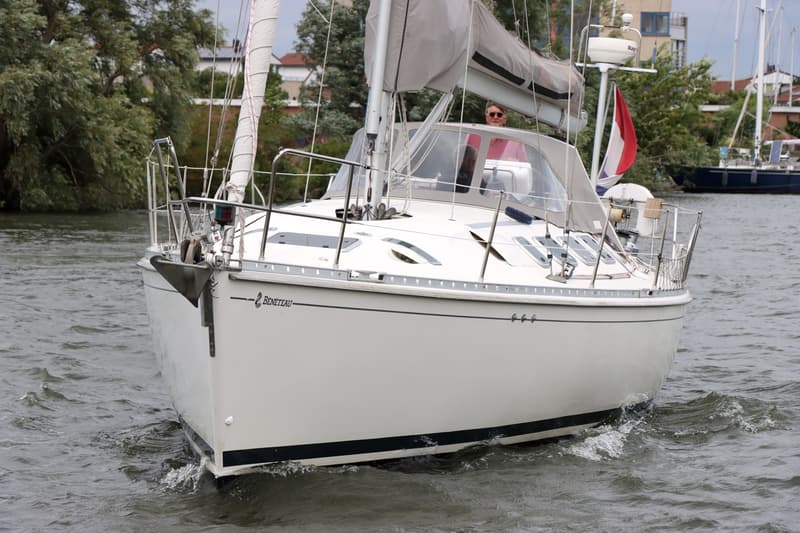 Een witte zeilboot met de naam "Bénéteau" op de boeg vaart op het water, met een persoon in de kuip. — Beneteau First 41S5