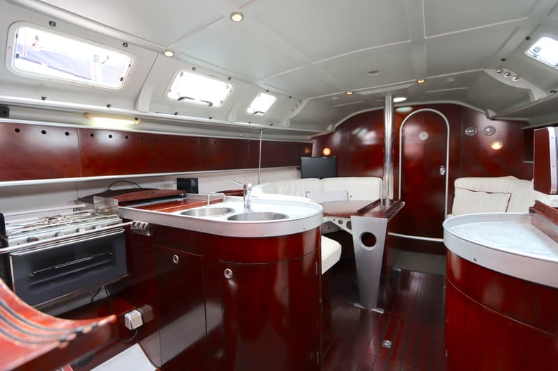 De foto toont het interieur van een boot met een kombuis, zithoek en houten vloer en wanden. — Beneteau First 41S5