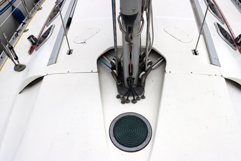 Een bovenaanzicht van het witte dek van een zeilboot met een mast en diverse lijnen en katrollen. — Beneteau First 41S5