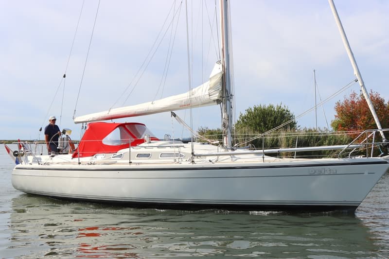De foto toont het interieur van een boot met een kombuis, een eettafel en zitbanken. — Dehler 36 CWS