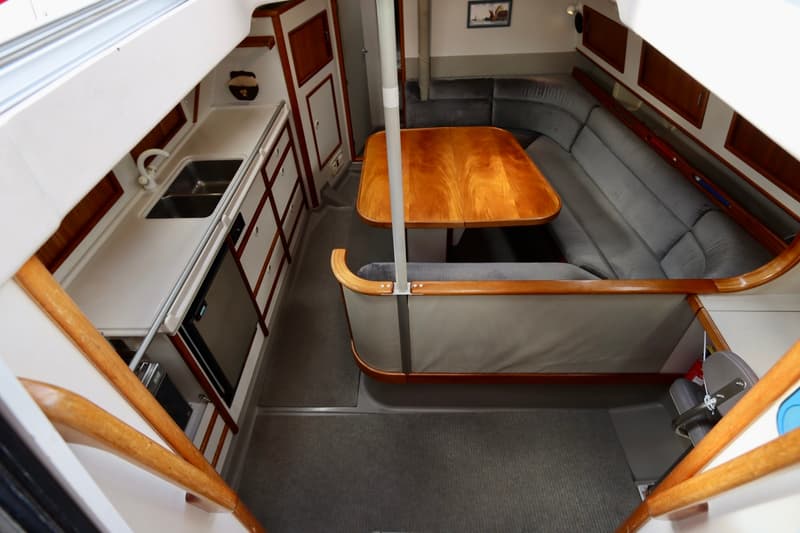 De foto toont het interieur van een boot met een kombuis aan bakboord en een dinette aan stuurboord. — Dehler 36 CWS