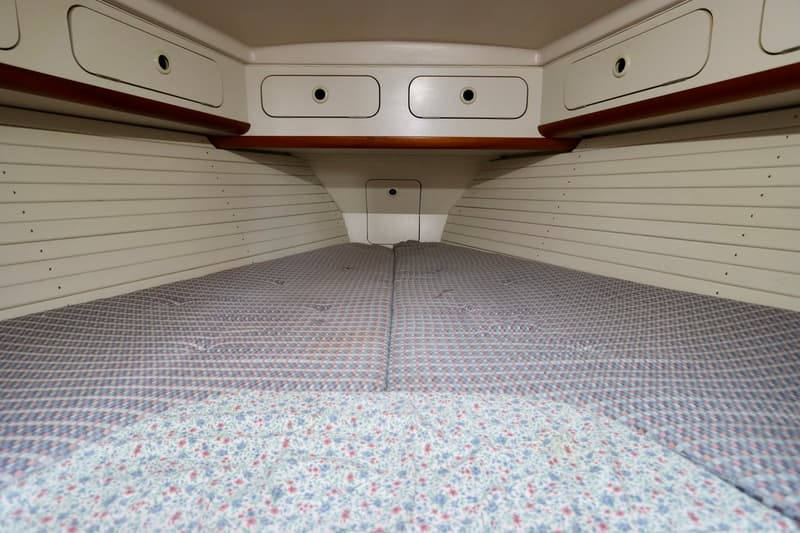 De foto toont een kajuit met een V-vormig bed met twee matrassen en een bloemenpatroon deken. — Dehler 36 CWS