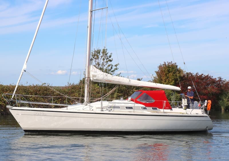 Een witte zeilboot met de naam "Delta" op de boeg en een rode buiskap vaart op het water. — Dehler 36 CWS