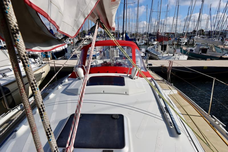 Een witte zeilboot met een rode buiskap ligt in een jachthaven, omringd door andere boten. — Dehler 36 CWS