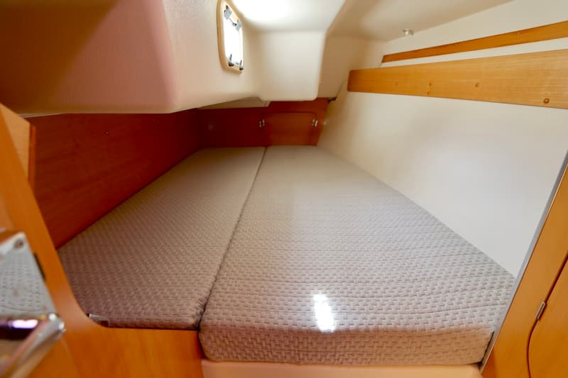 Een kajuit met een tweepersoonsbed, houten afwerking, een klein raam en een opbergplank is zichtbaar. — Etap 30i