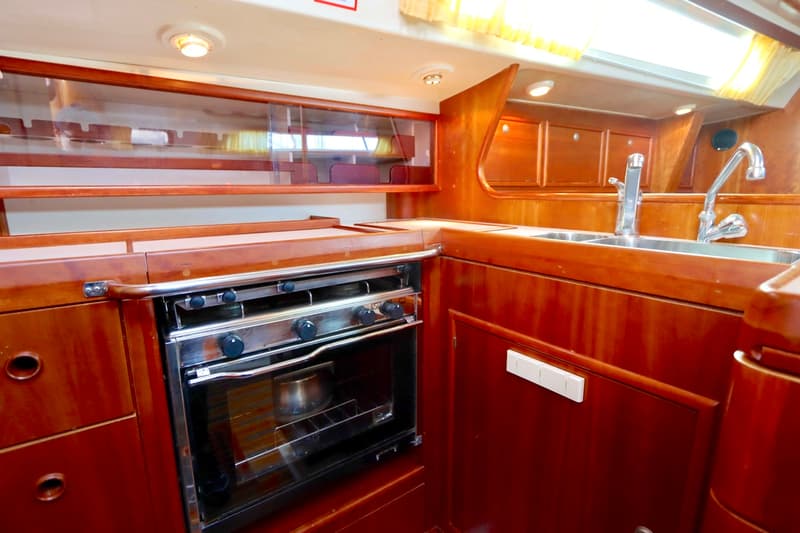 Een kombuis met een roestvrijstalen oven/fornuis, twee spoelbakken met kranen en houten kasten en panelen.