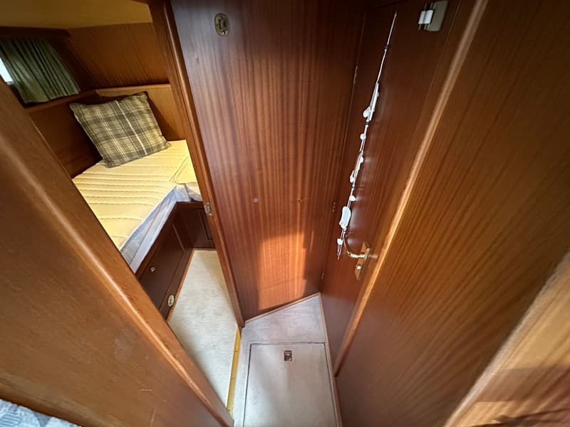 Een kajuit met een bed, een kussen, een raam met gordijn en een houten interieur. — Boarncruiser 1000