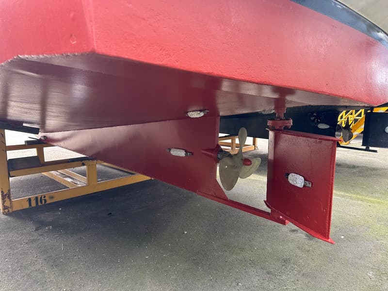 Een detailfoto van de onderkant van een rode boot met een schroef en roer, staand op een gele bok. — Boarncruiser 1000