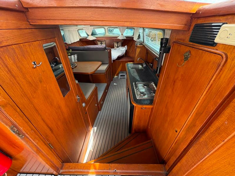 De foto toont het interieur van een boot met houten wanden, een kombuis en een zithoek. — Valk Sport