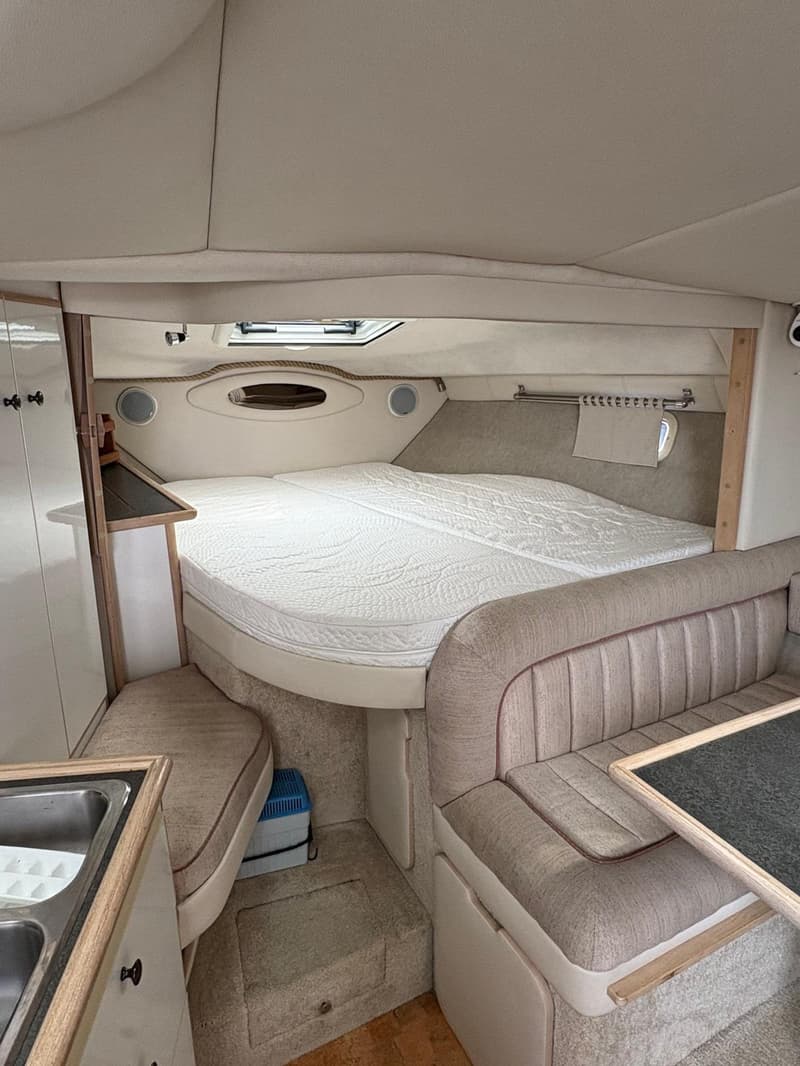 De foto toont het interieur van een boot met een bed, een bank, een tafel en een gootsteen. — Maxum 3200 SCR