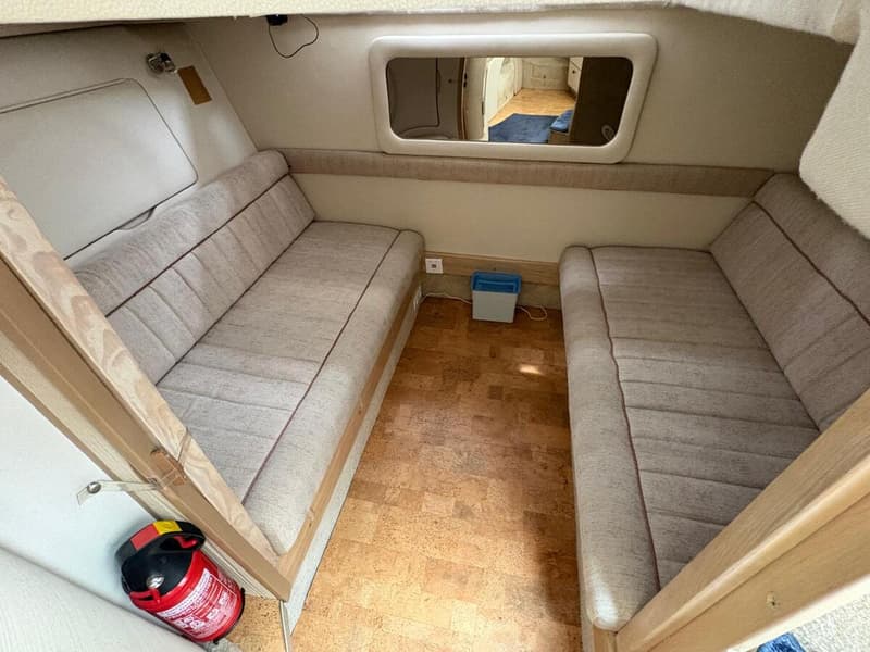 De foto toont een kajuit met twee banken met stoffen bekleding, een kurken vloer en een brandblusser. — Maxum 3200 SCR