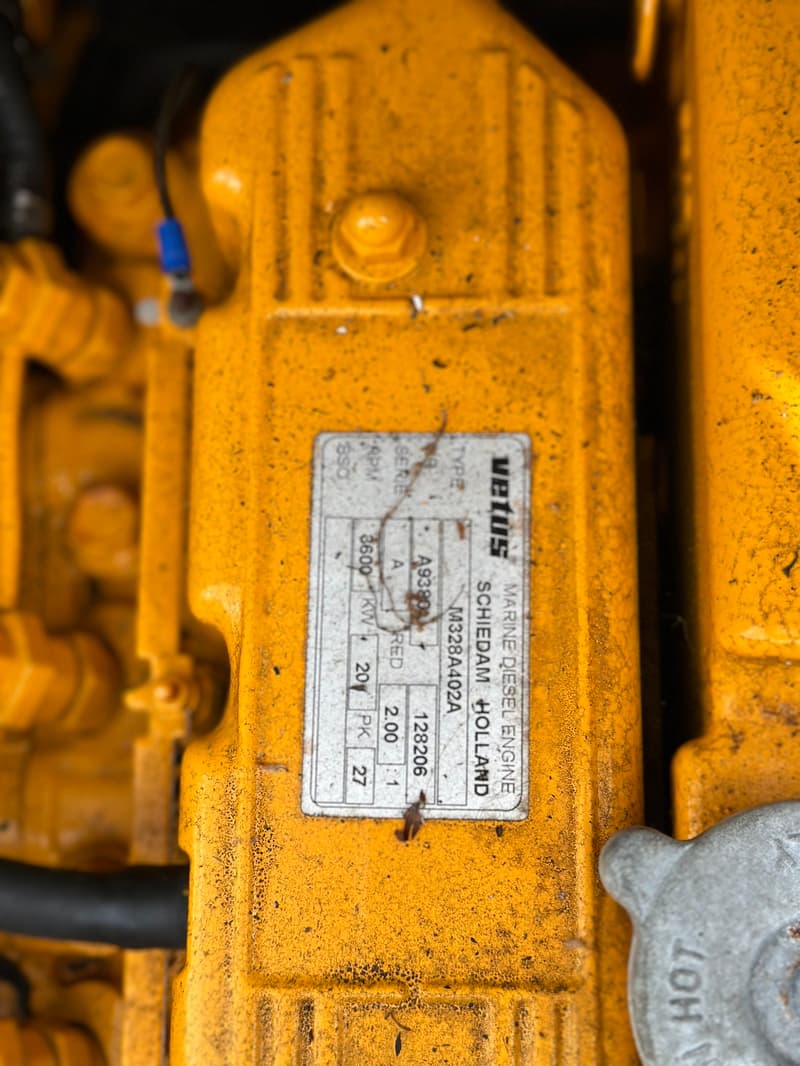 Een close-up van een gele Vetus scheepsdieselmotor met een specificatielabel.