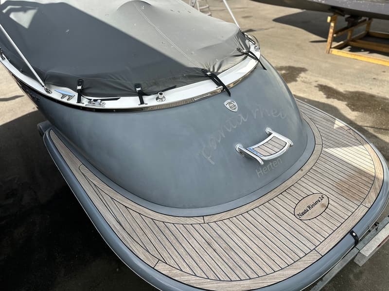 Een grijze boot met een houten dek en een grijze afdekhoes, met de naam "panta rhei" en "Herten" erop. — Riviera 24