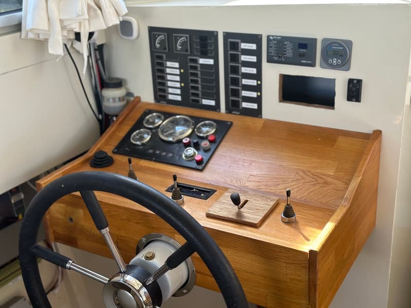 Een stuurwiel met een houten dashboard met diverse meters en schakelaars.