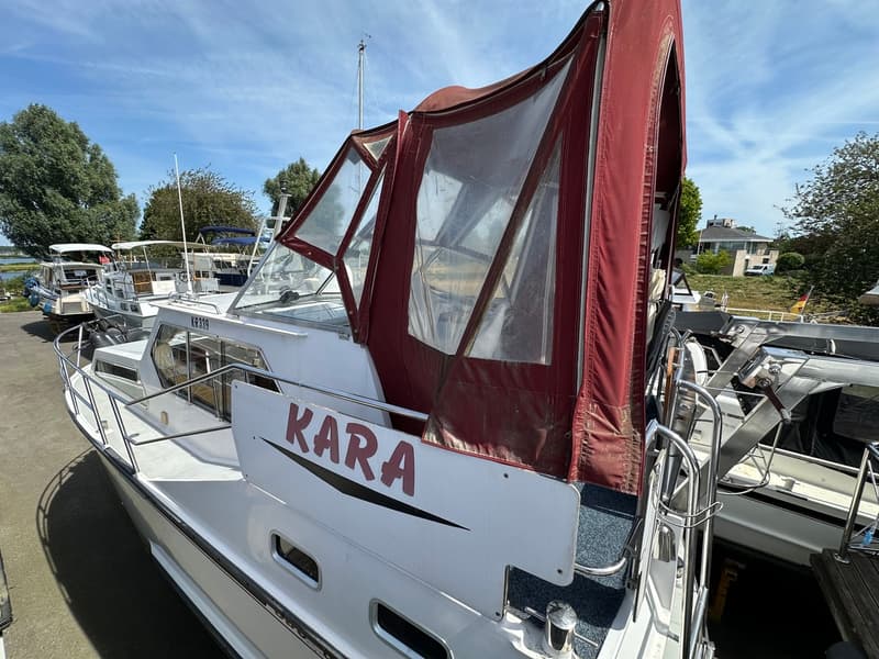 Een witte motorboot met de naam "KARA" in rode letters op de zijkant, met een rode cabriokap. — Succes Ultra 500