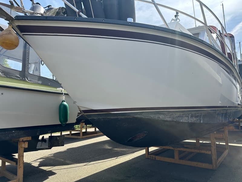 Een witte boot met bruine strepen en een donkere onderkant staat op houten bokken naast een andere boot. — Succes Ultra 500