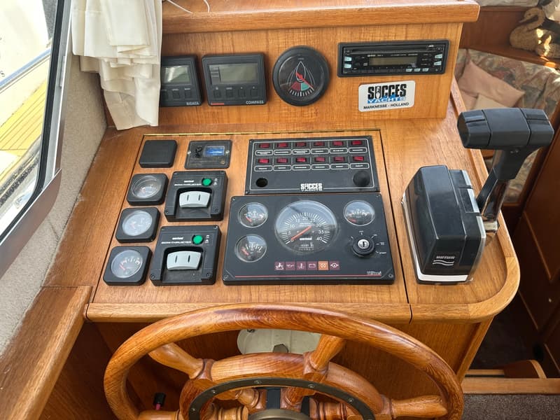 Een houten dashboard met diverse meters, schakelaars, een stuurwiel en een gashendel.