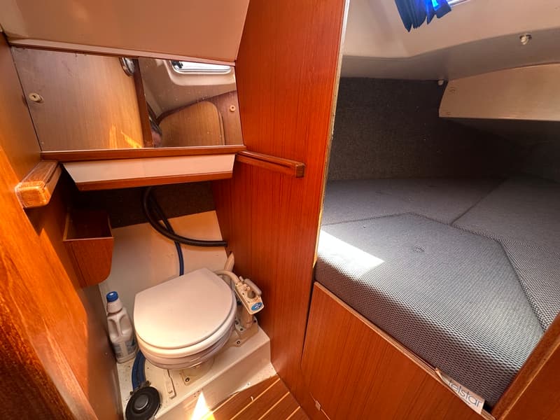 De foto toont een bootinterieur met een toiletruimte en een slaapgedeelte met een matras.