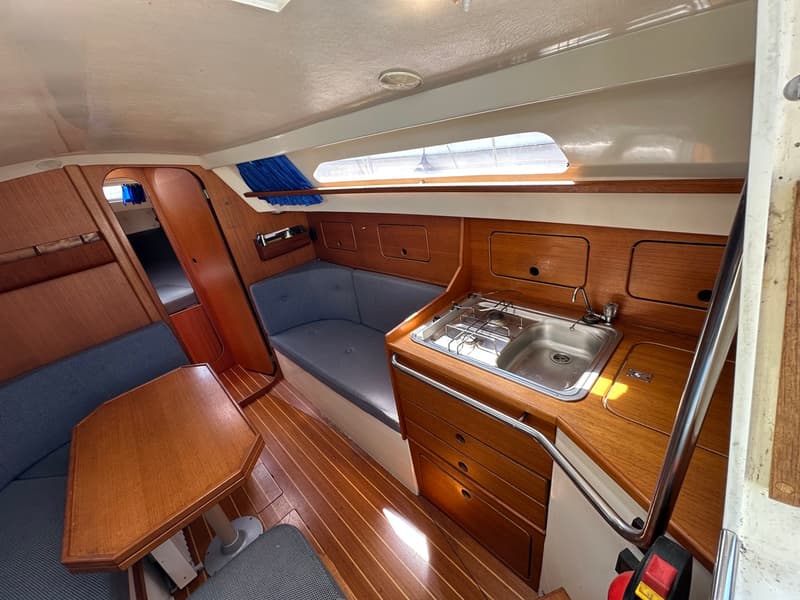 De foto toont het interieur van een boot met een kombuis, zithoek en een doorgang naar een slaapcabine. — Compromis 777