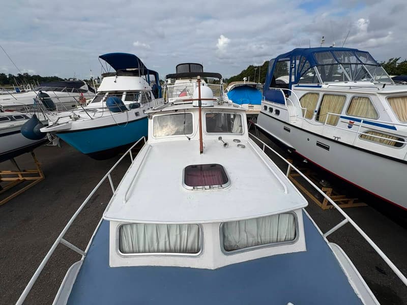 Een bovenaanzicht van de boeg van een blauw-witte boot, met andere boten op de achtergrond. — Smelne 950 ak