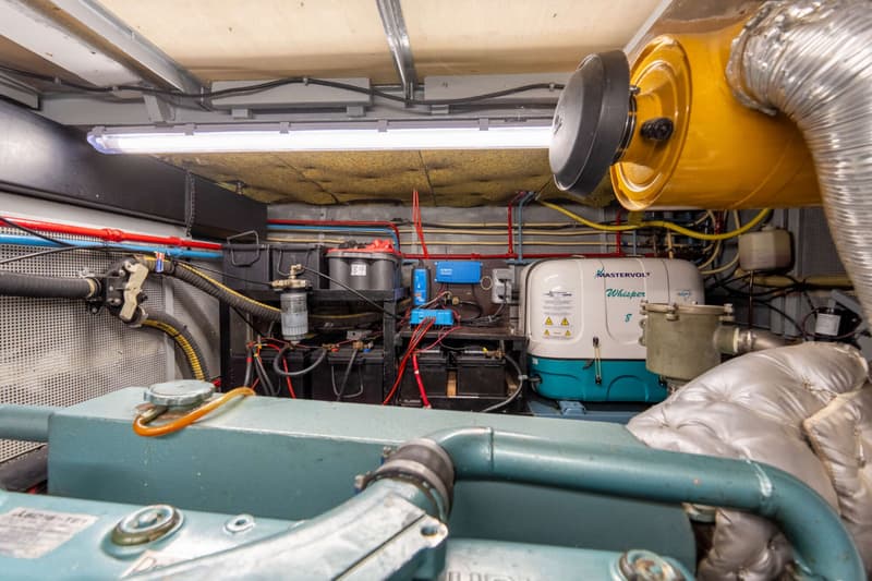 De foto toont een motorruimte met een Mastervolt Whisper 8 generator, accu's, leidingen en een deel van een motor.
