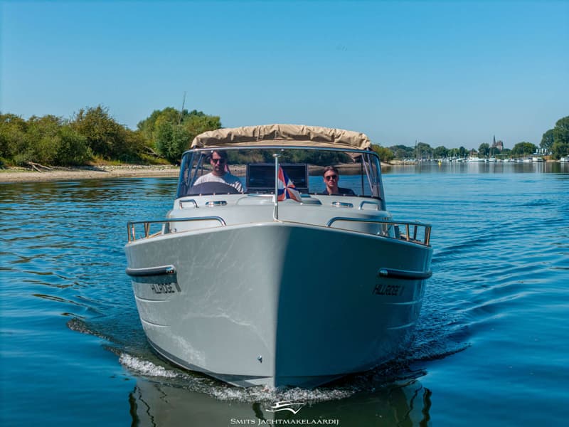 Een grijze motorboot met twee mannen aan boord vaart op een zonnige dag over rustig water. — Antaris Antaris Seventy7 Cabin