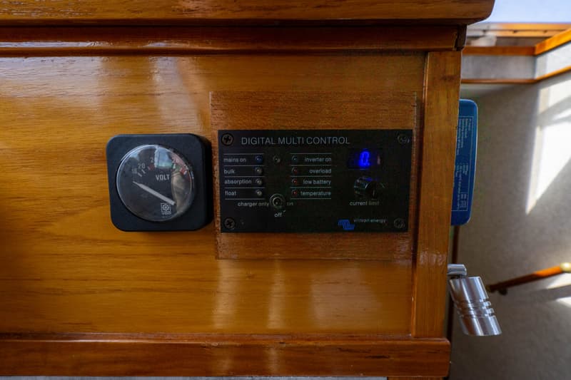 Een houten paneel met een VDO voltmeter en een Victron Energy digitaal multi control paneel.