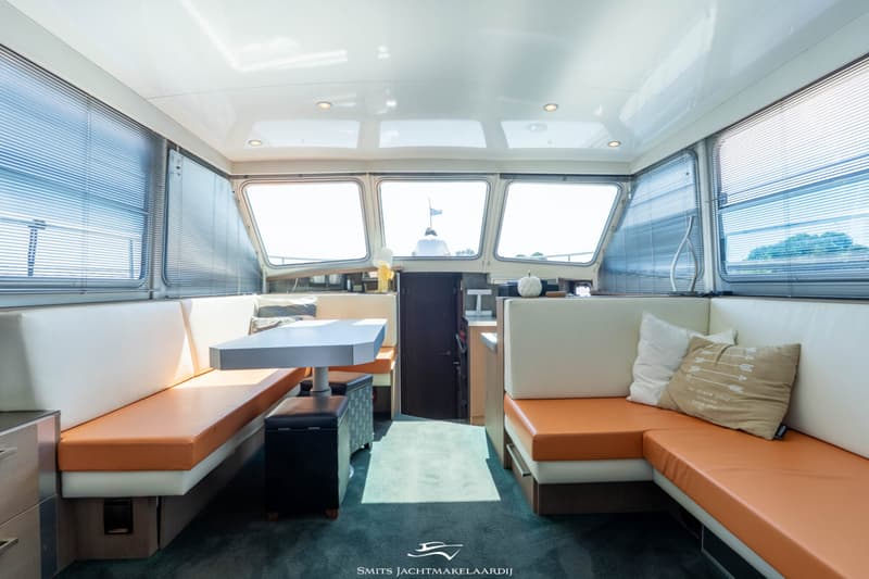 De foto toont het interieur van een boot met een zithoek, een tafel en ramen met jaloezieën. — Bekebrede Bekebrede Myco 45 SL