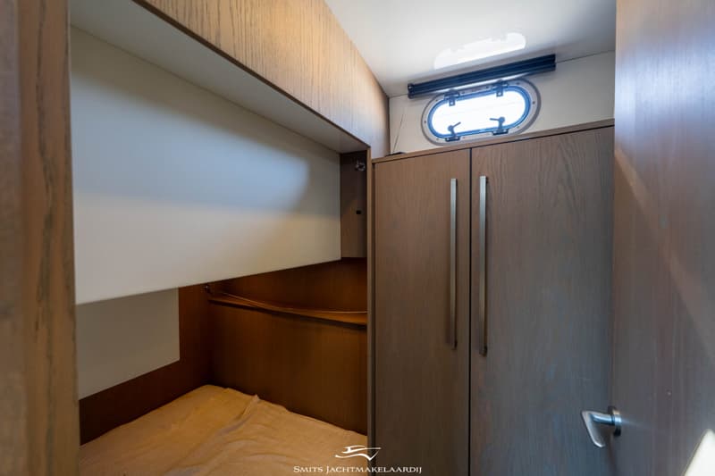 Een kajuit met een bed, een kast met twee deuren en een patrijspoort met een luik erboven. — Bekebrede Bekebrede Myco 45 SL