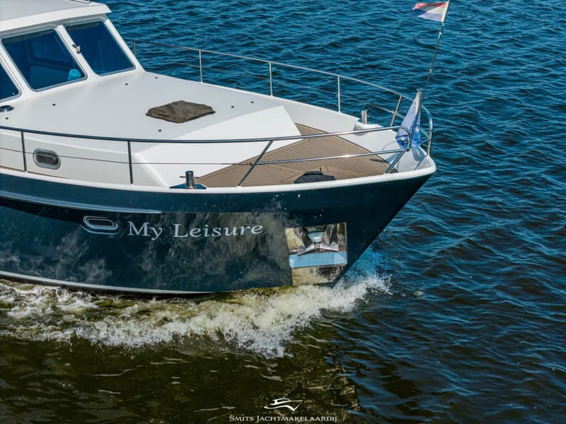 Een donkerblauwe boot met witte opbouw en de naam "My Leisure" op de boeg vaart door het water.