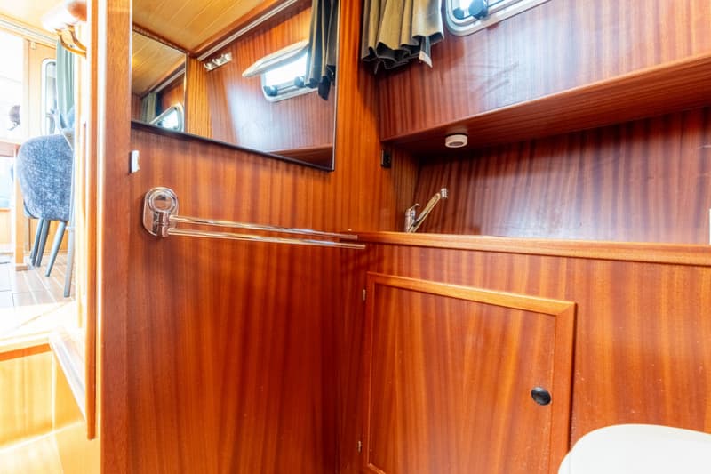 Een interieur van een boot met houten wanden, een spiegel, een wasbak en een handdoekrek. — Bege Bege 1000 OK Spiegeldeur