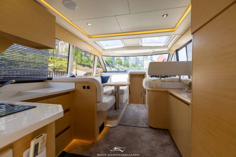 De foto toont het interieur van een boot met een keukenblok, zithoek en stuurstand. — Greenline Greenline 39