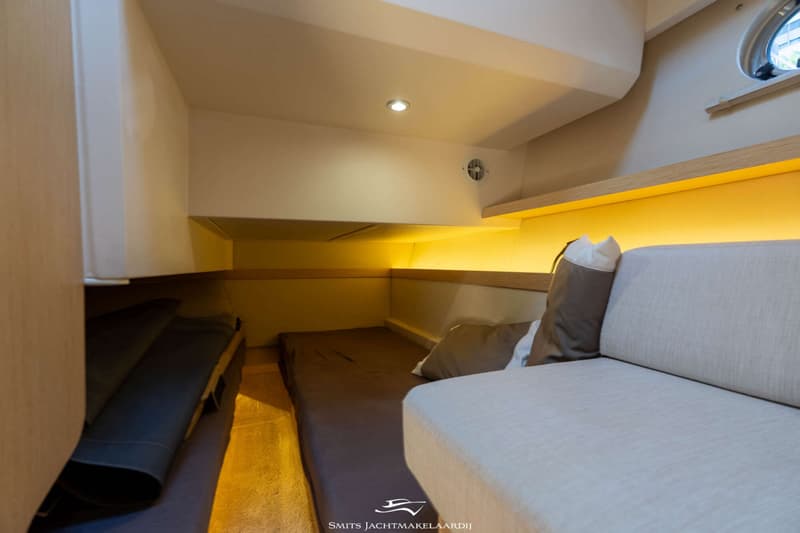 De foto toont een kajuit met een bed, een bank met kussens, een patrijspoort en verlichting. — Greenline Greenline 39
