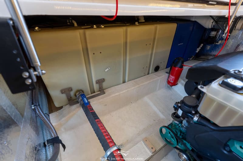 Een detailfoto van een motorruimte met een motor, tanks, slangen en een brandblusser.