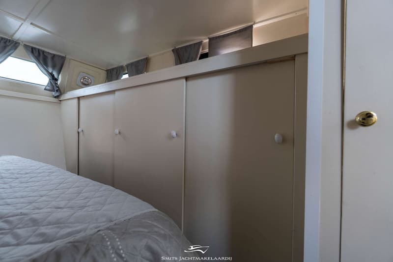 Een slaapkamer met een bed, schuifdeurkasten, ramen met gordijnen en een plafondventilator.