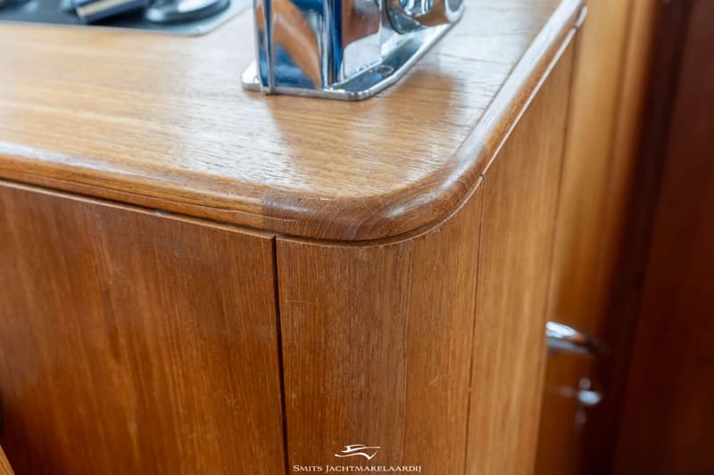Een close-up van een houten kastje met een afgeronde bovenrand en een metalen handvat bovenaan.