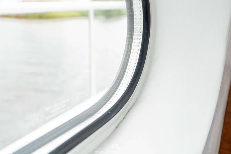 Een close-up van een rond patrijspoort met een zilveren rand en een zwarte rubberen afdichting.