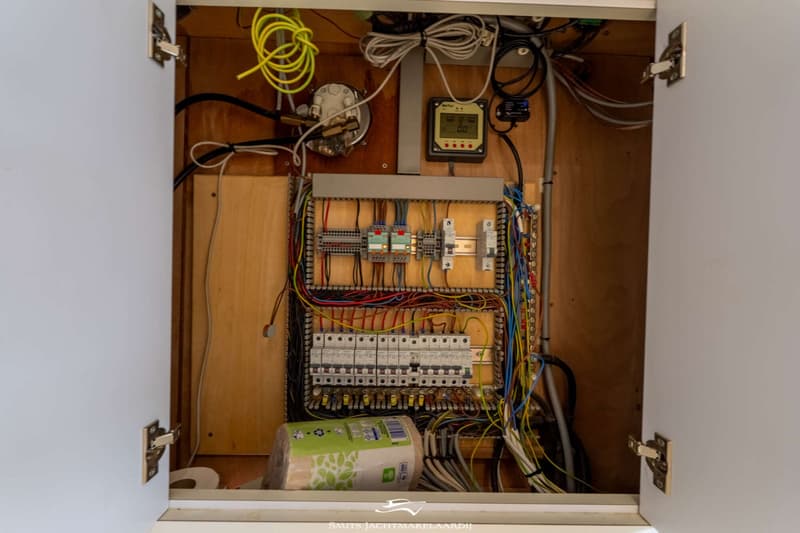 Een open kast met een uitgebreid elektrisch paneel, diverse draden, schakelaars en een digitaal display.